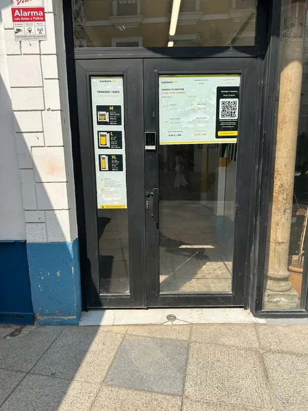 Puerta negra de acceso a Lockers Olé en calle Regina, Sevilla